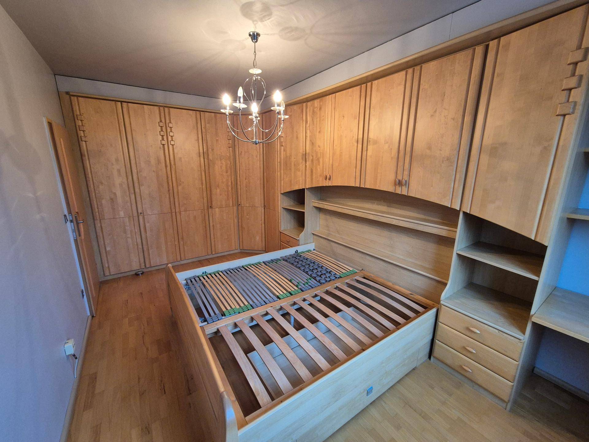 Schlafzimmer mit großem Einbauschrank und Holzbettrahmen, bietet viel Stauraum.