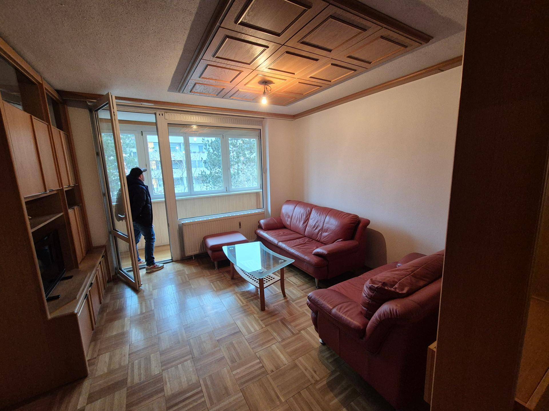 Gemütliches Wohnzimmer mit roten Ledersofas, Parkettboden und einer Holzdeckenverkleidung.