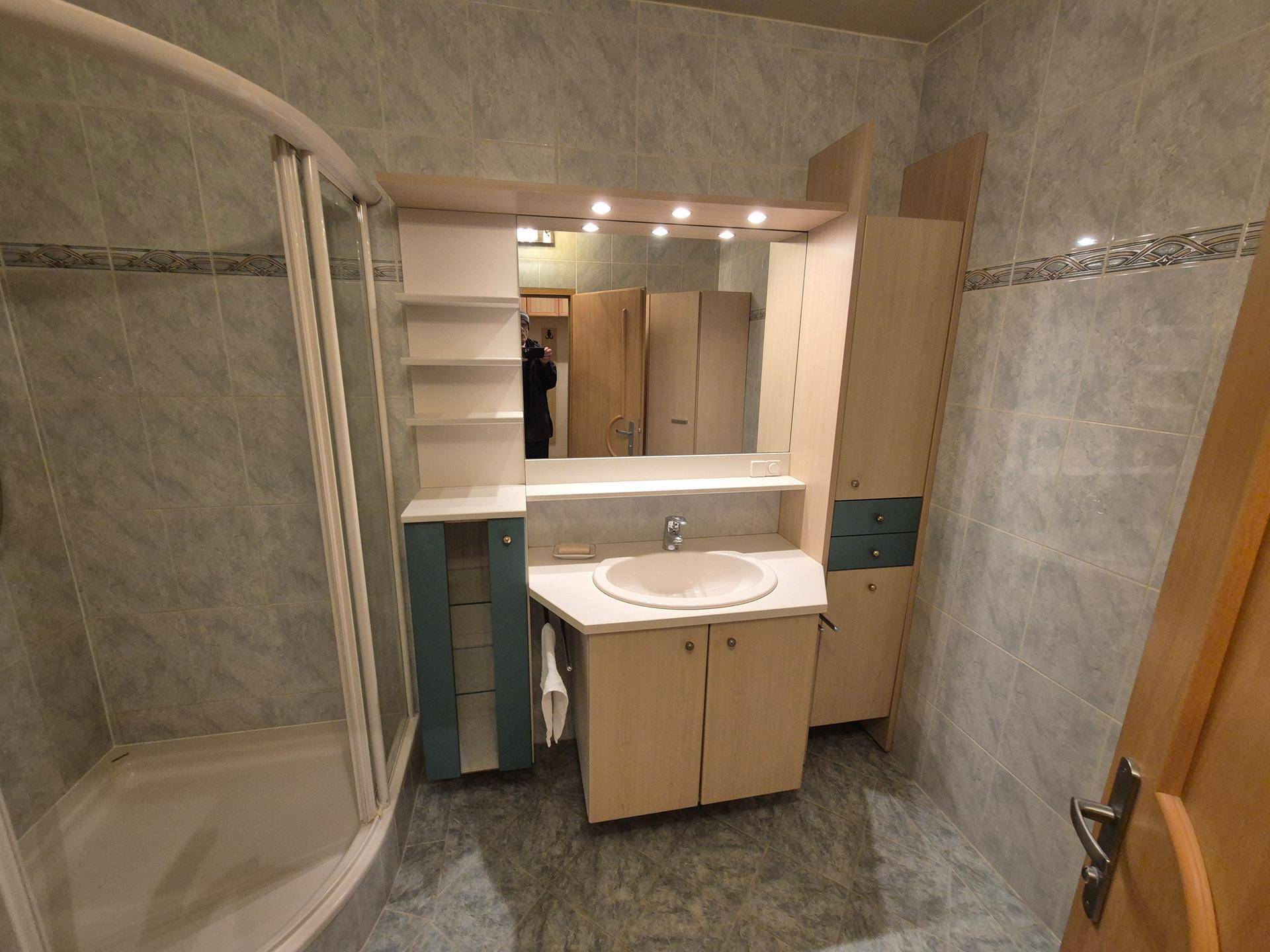Badezimmer mit Einzelwaschbecken, Spiegelschrank und integrierten Ablagen in hellem Holzdesign.