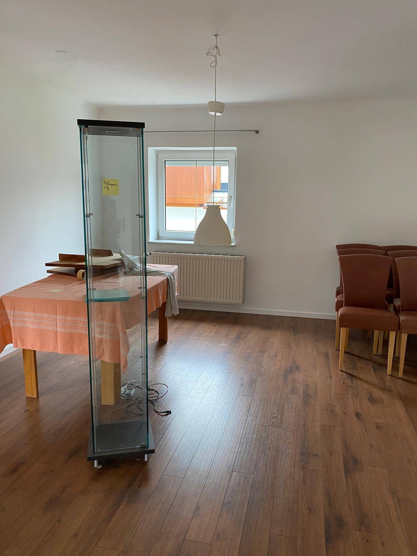 Essbereich mit Laminatboden, Fenster und einem Glasvitrinenschrank.