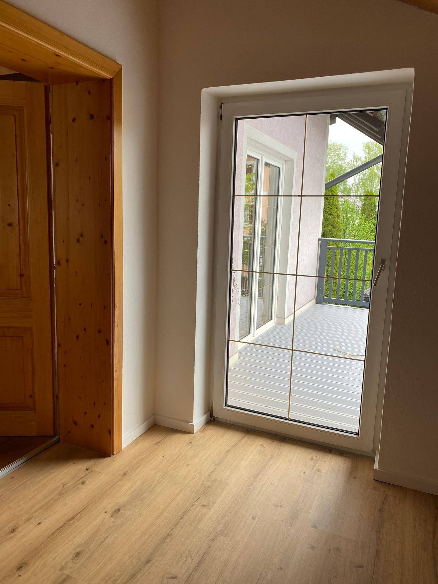 Heller Raum mit Holztürrahmen und Zugang zu einem Balkon.