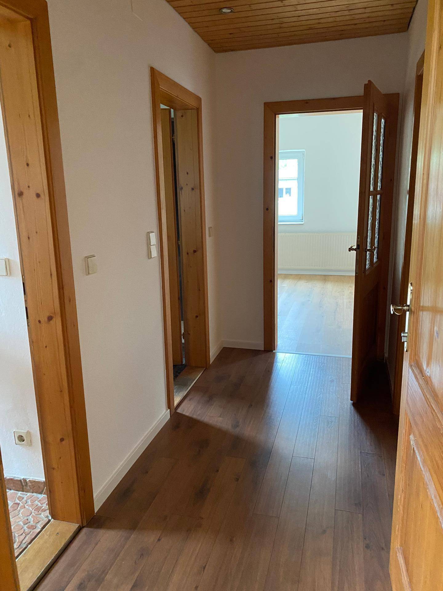 Heller Flur mit Laminatboden und mehreren Holztüren zu angrenzenden Räumen.