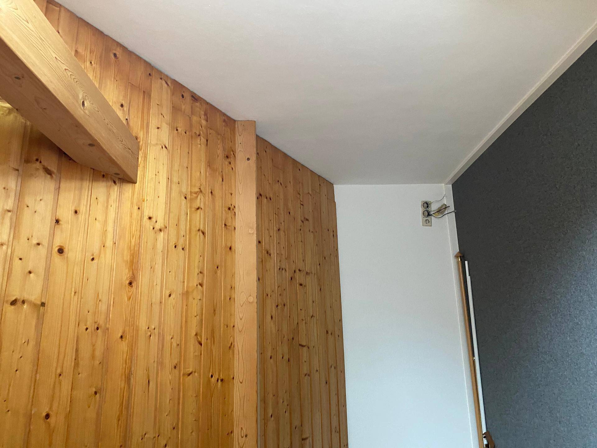 Innenraum mit markanter Holzverkleidung, weißer Decke und sichtbarem Holzbalken, der Charakter verleiht.