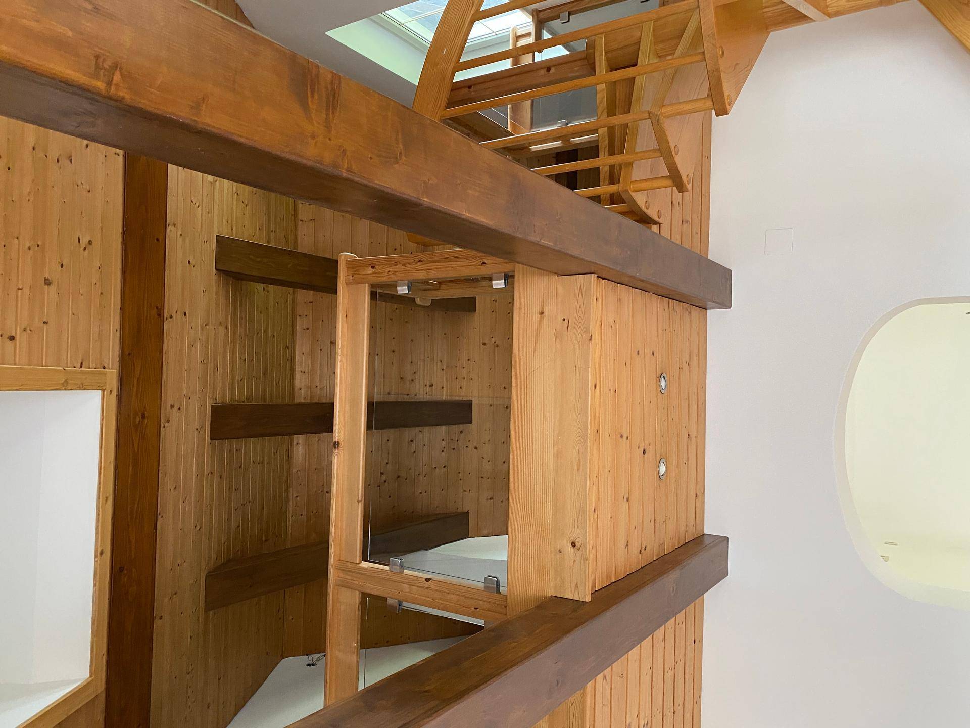 Innenansicht mit Holzverkleidung, Regalen und sichtbaren Deckenbalken.