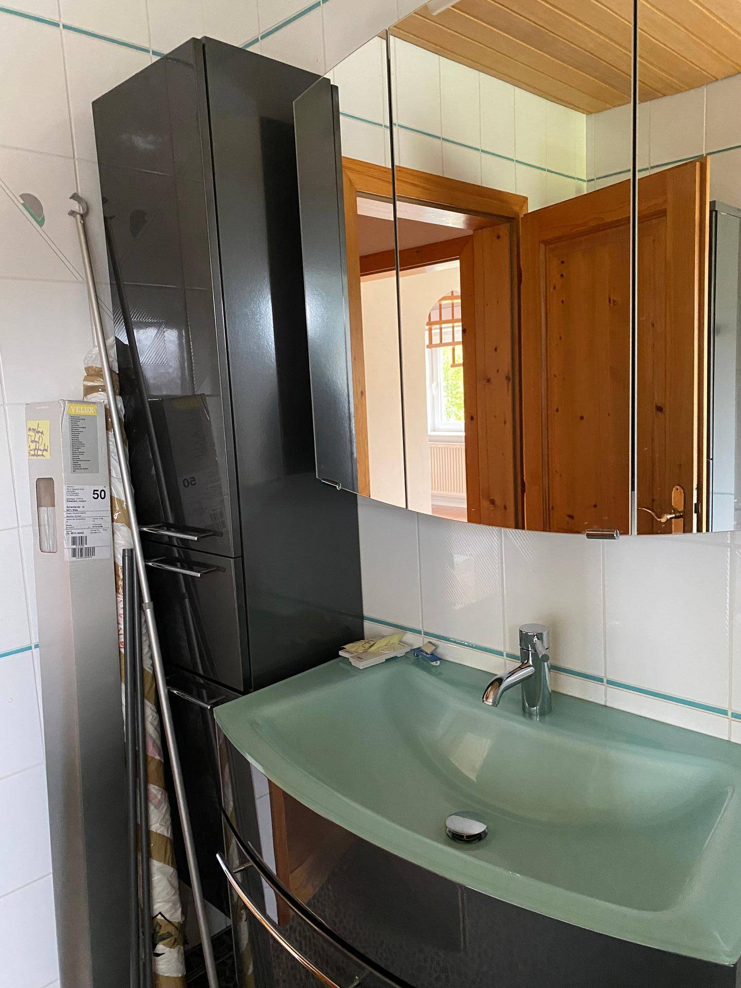 Badezimmer mit modernem Waschtisch, Spiegelschrank und dunklen Möbeln.
