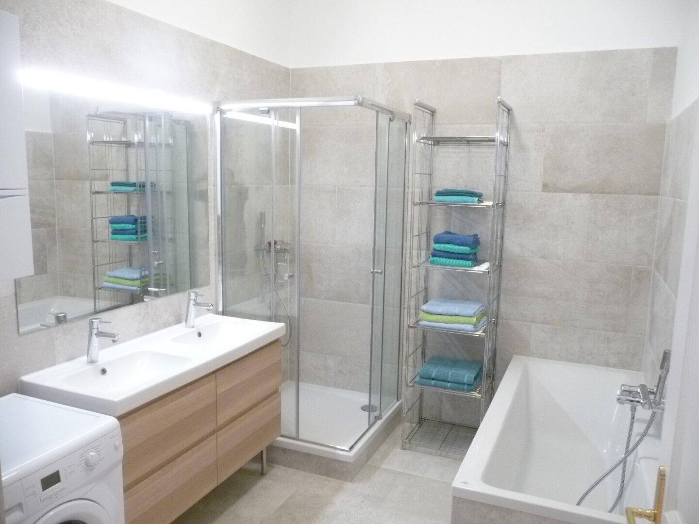 Modernes Badezimmer mit Doppelwaschbecken, Duschkabine und Badewanne.