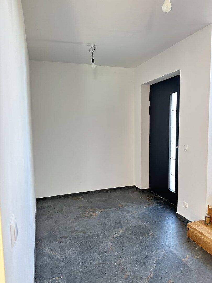 Eingangsbereich mit dunklem Fliesenboden und moderner Haustür, hell und einladend.