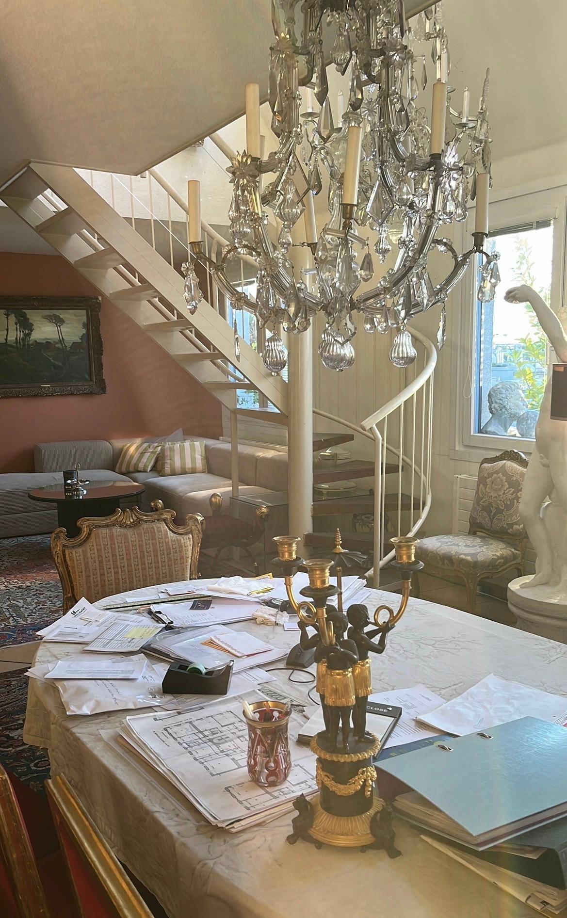 Elegantes Wohnzimmer mit einem prächtigen Kristallleuchter und einer geschwungenen Wendeltreppe.