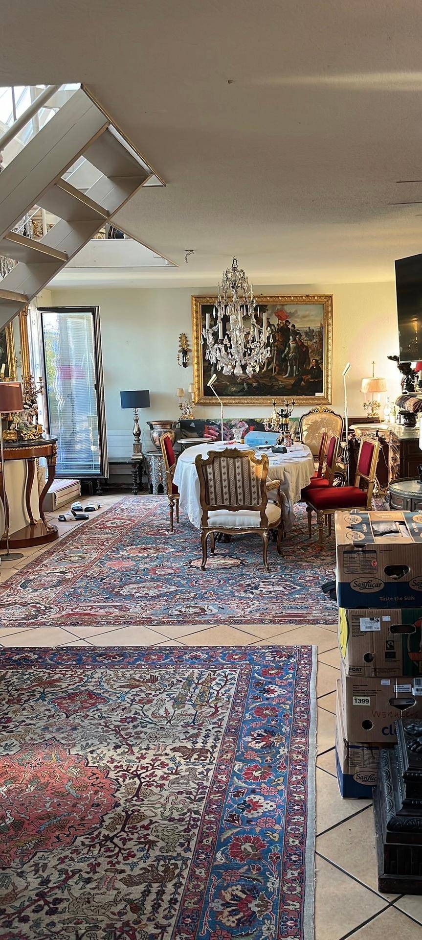 Geräumiger Wohn-Essbereich mit opulenten Teppichen, einem großen Gemälde und einem Kristallleuchter.