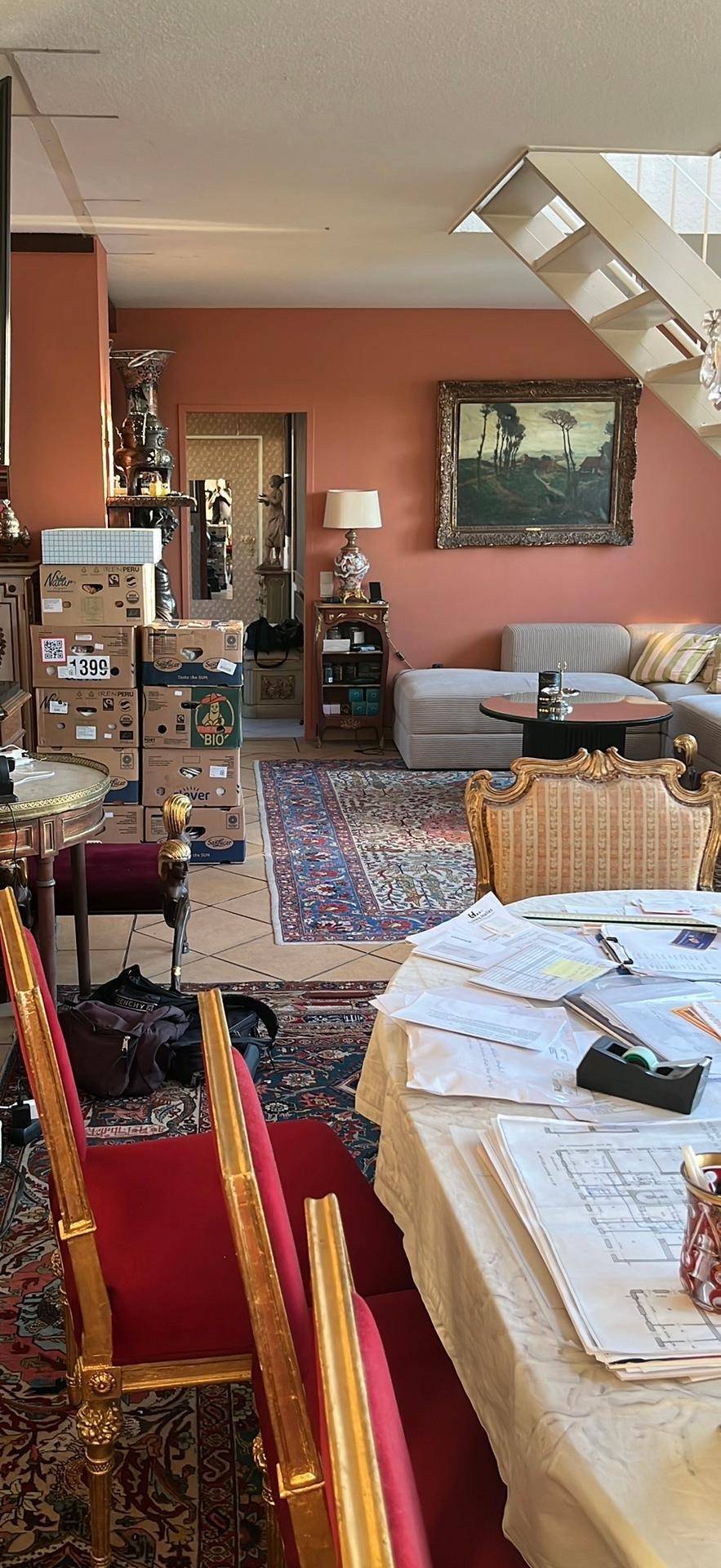 Wohn-Essbereich mit roten Stühlen, einem Sofa und einer Treppe, die in den oberen Bereich führt.