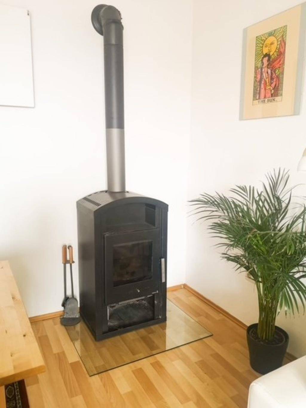 Detailansicht eines modernen Holzofens mit Glasplatte im Essbereich.