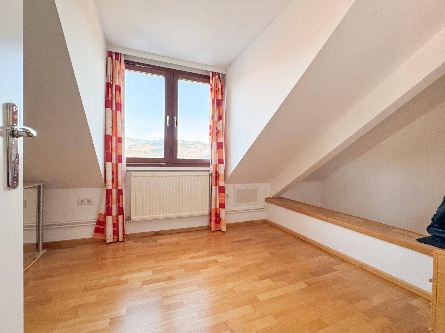 Dachgeschosszimmer mit Holzboden und schrägen Wänden, bietet Potenzial für gemütliches Wohnen.
