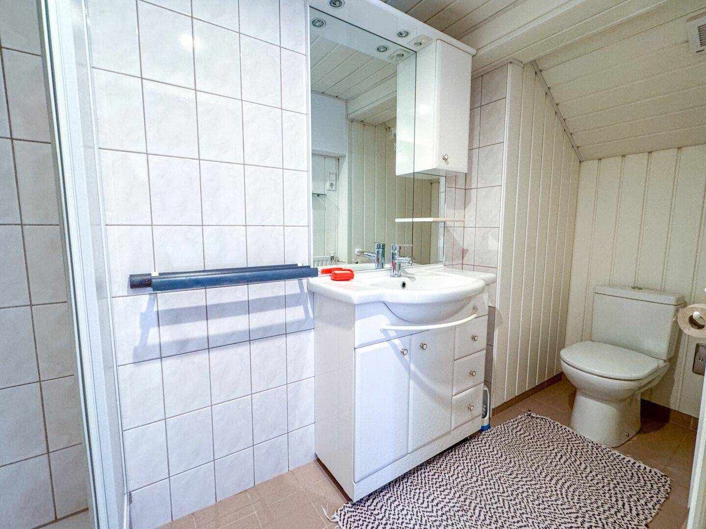 Funktionales Badezimmer mit Dusche, Waschbecken und WC, in gutem, aber älterem Zustand.