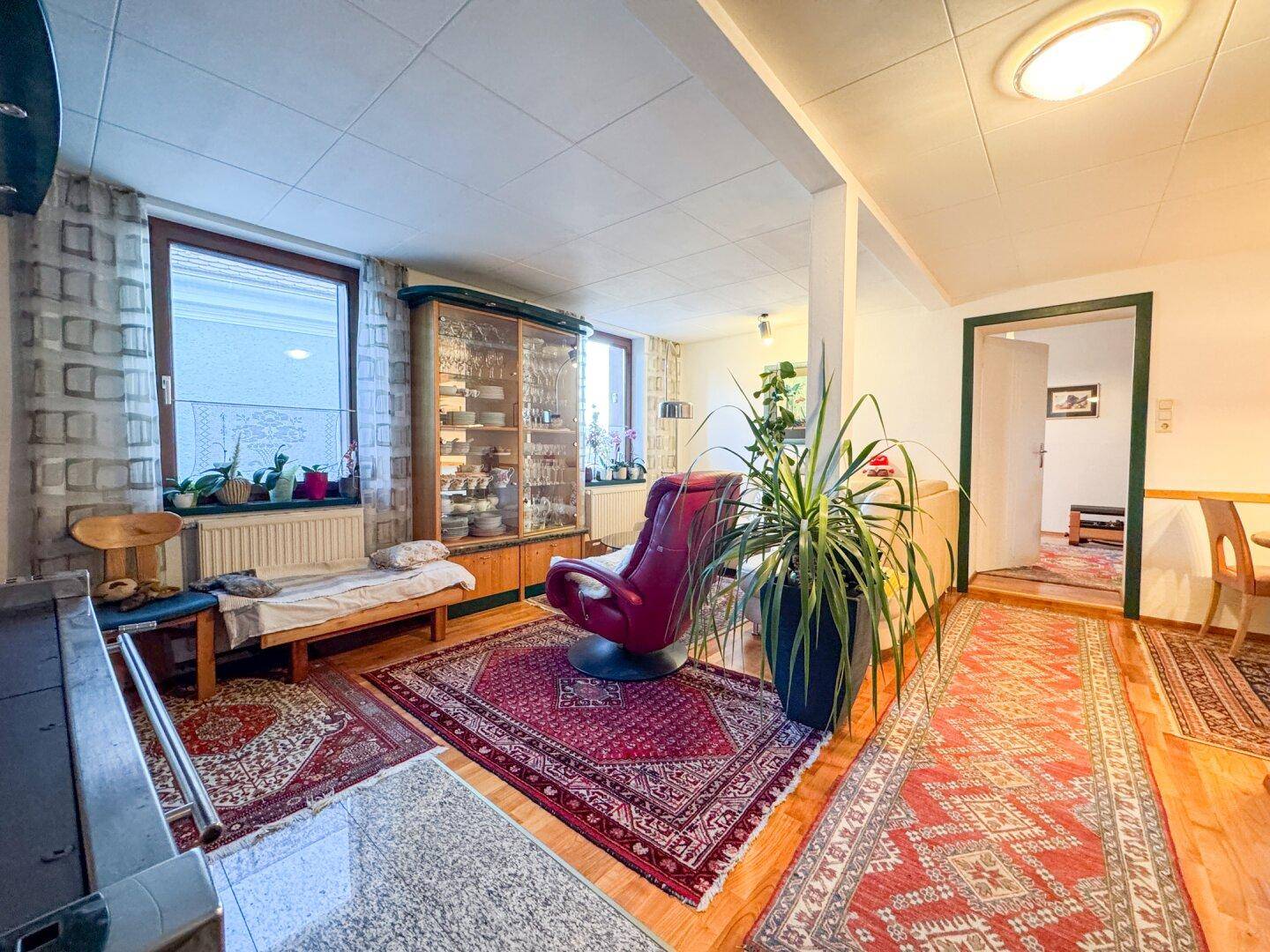Geräumiges Wohnzimmer mit Holzboden und traditionellen Teppichen, bietet viel Platz.