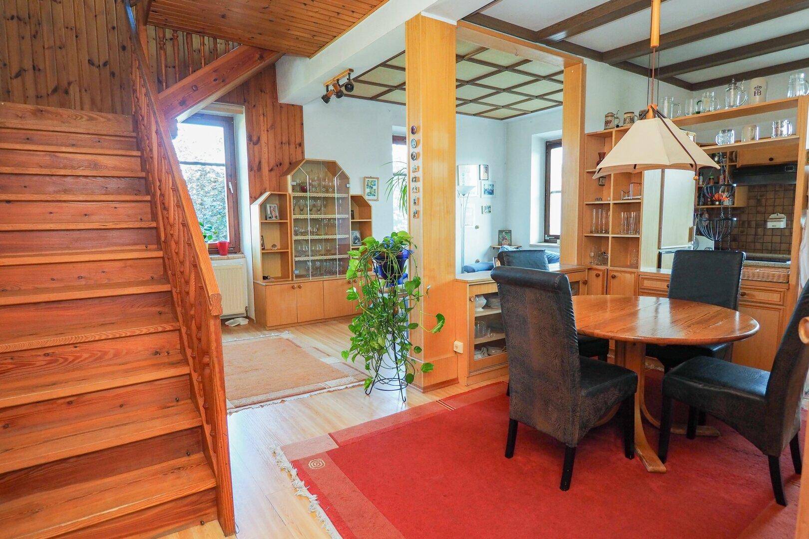 Offener Essbereich mit Holztreppe, Holzboden und Regalen, verbindet Wohn- und Essbereich.