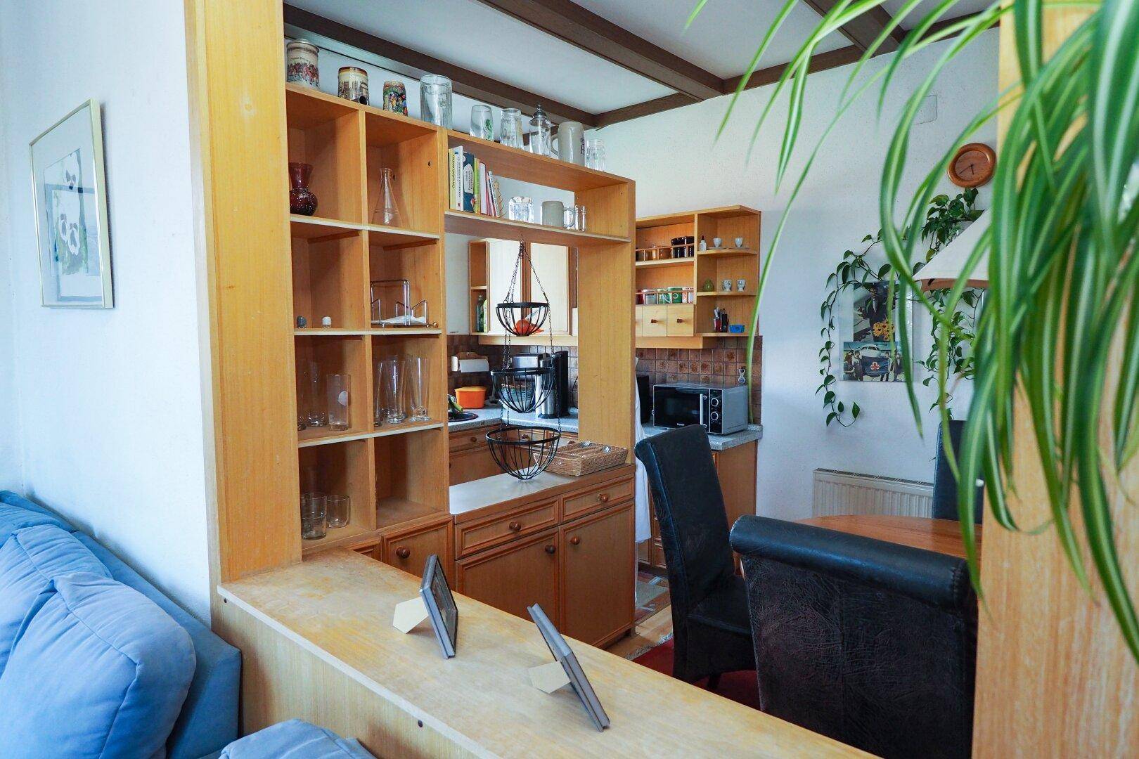 Halboffene Küche mit Holzmöbeln und Essbereich, integriert in den Wohnraum.