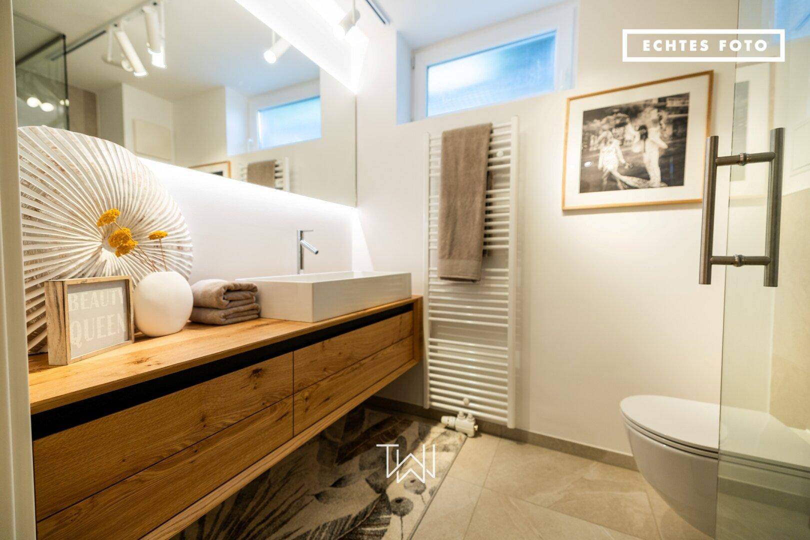 Elegantes Badezimmer mit modernem Waschtisch, wandhängendem WC und beheiztem Handtuchhalter.