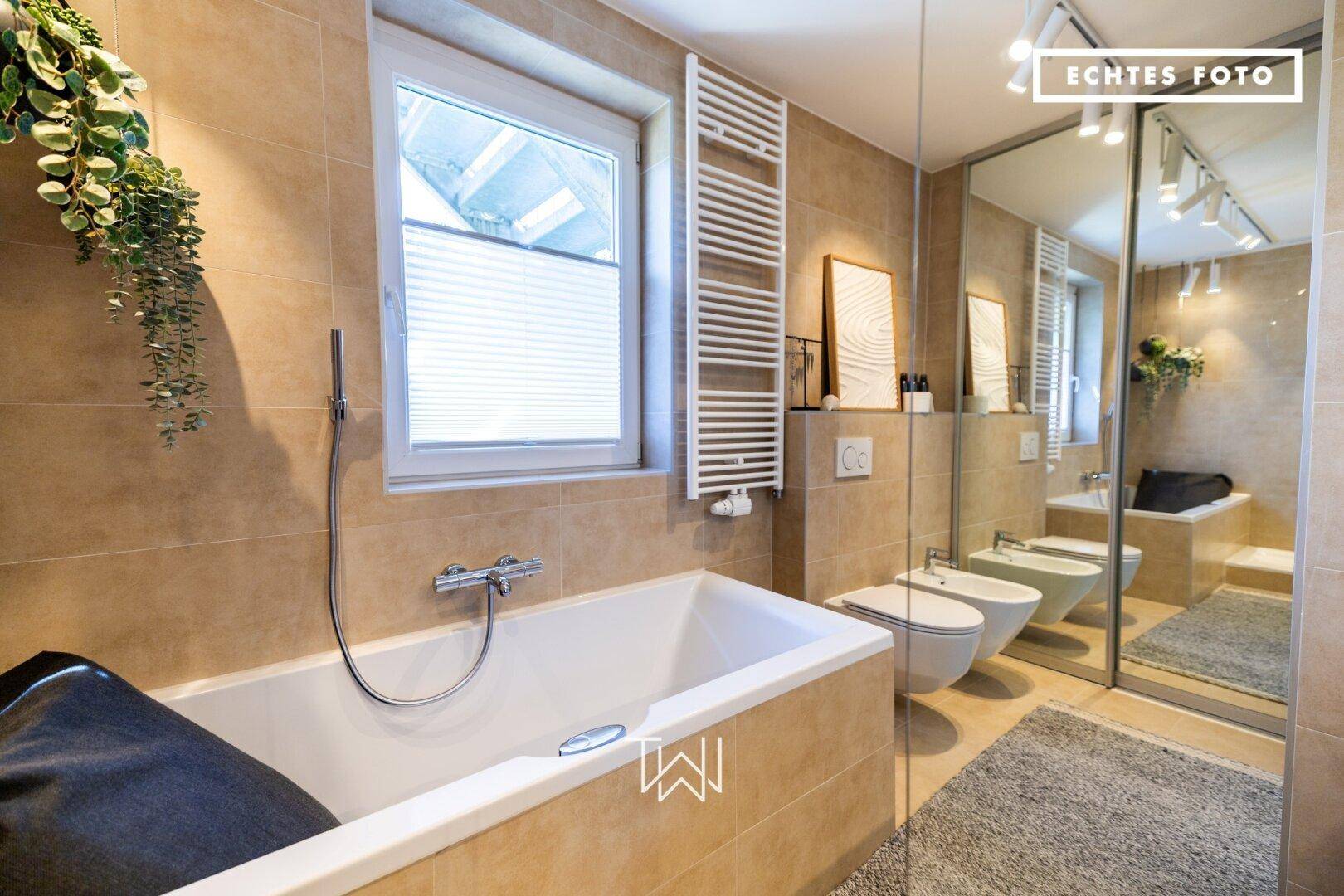 Modernes Badezimmer mit Badewanne, Bidet, Doppelwaschbecken und großer Spiegelfront.