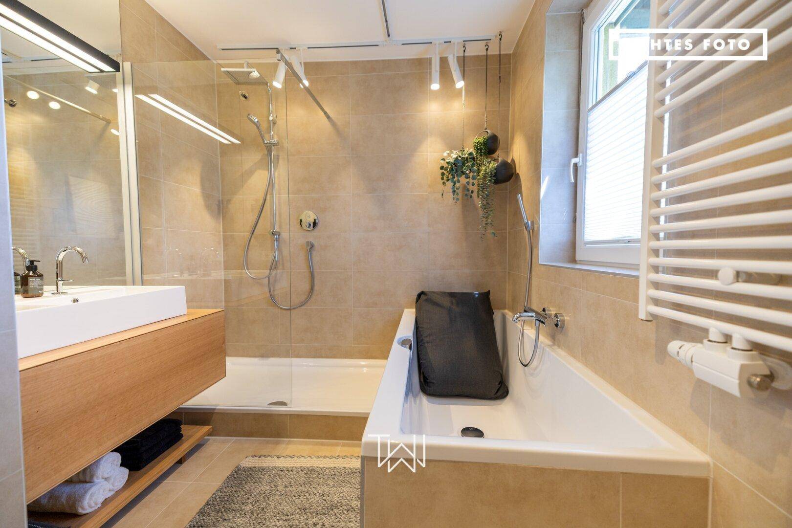 Helles Badezimmer mit Badewanne, begehbarer Dusche und modernem Waschtisch.