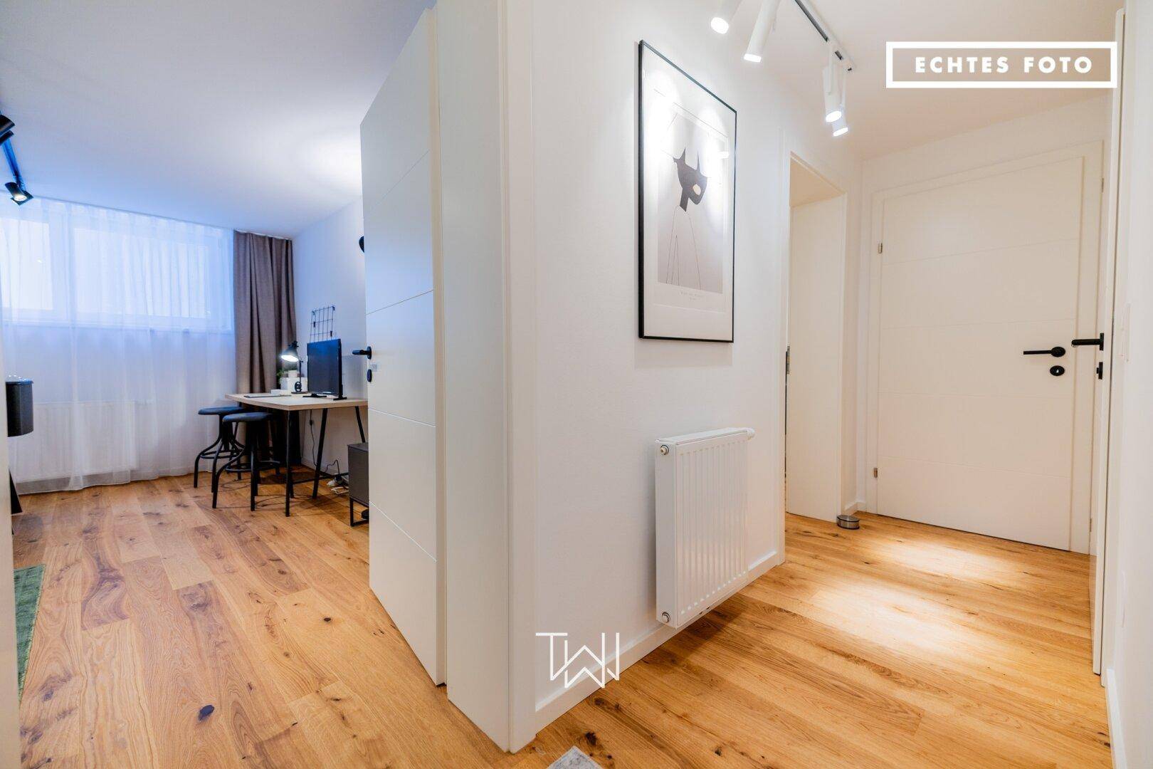 Funktionales Büro mit Holzboden, Heizkörper und ausreichend Platz für einen Arbeitsbereich.