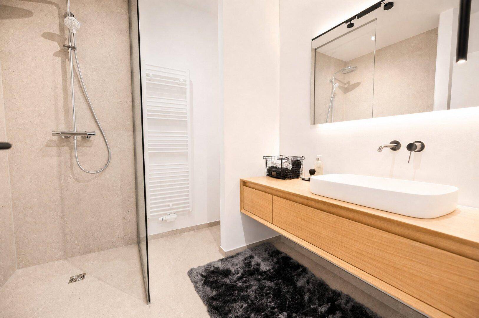 Modernes Badezimmer mit begehbarer Dusche, schwebendem Waschtisch und Handtuchheizkörper.