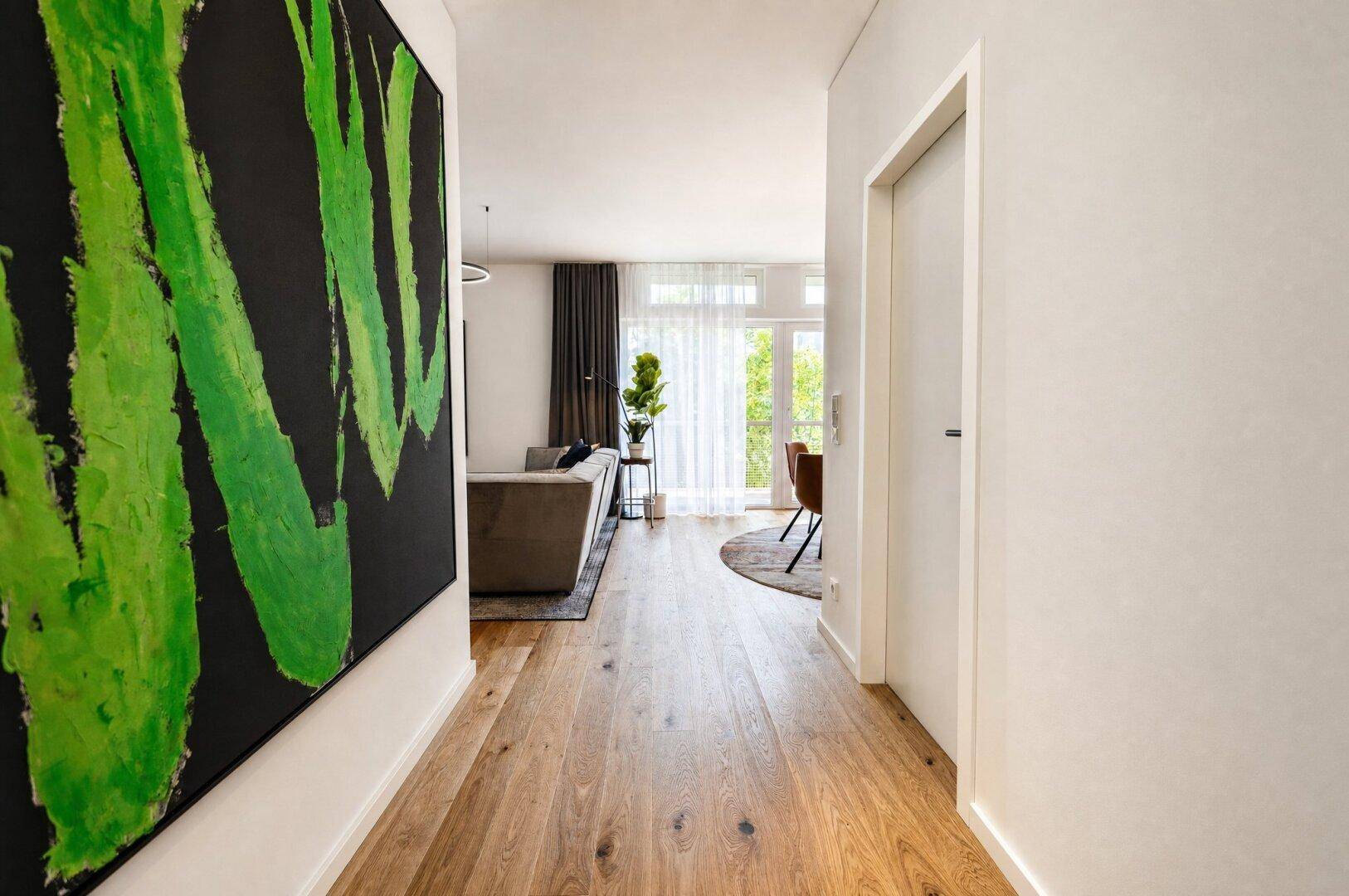 Heller Flur mit Holzboden und modernem Kunstwerk, der zum Wohnbereich führt.