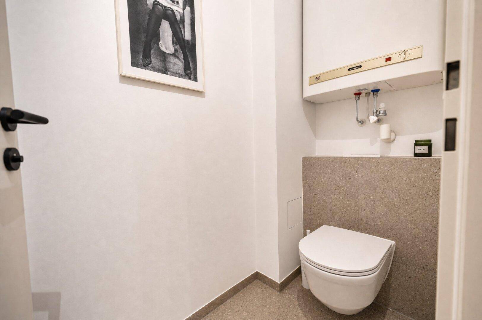Kleines Gäste-WC mit wandhängender Toilette und Warmwasserboiler.