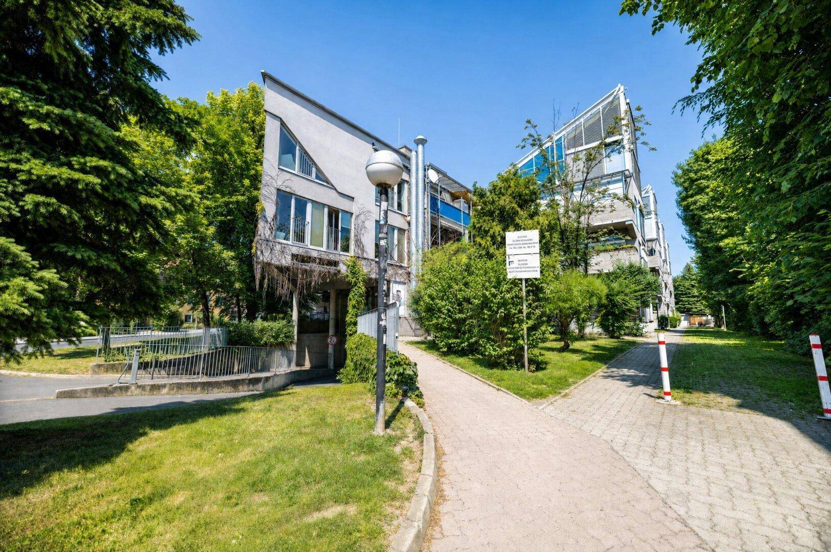 Modernes Mehrfamilienhaus mit viel Grün und gepflegten Außenanlagen.