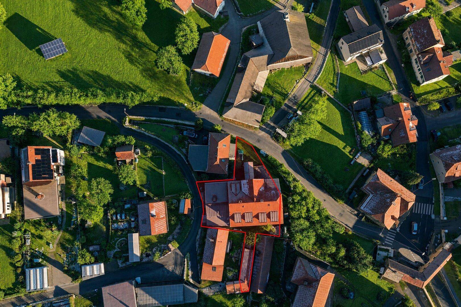 Luftaufnahme des Anwesens mit roter Umrandung, umgeben von grünen Feldern und Dächern.