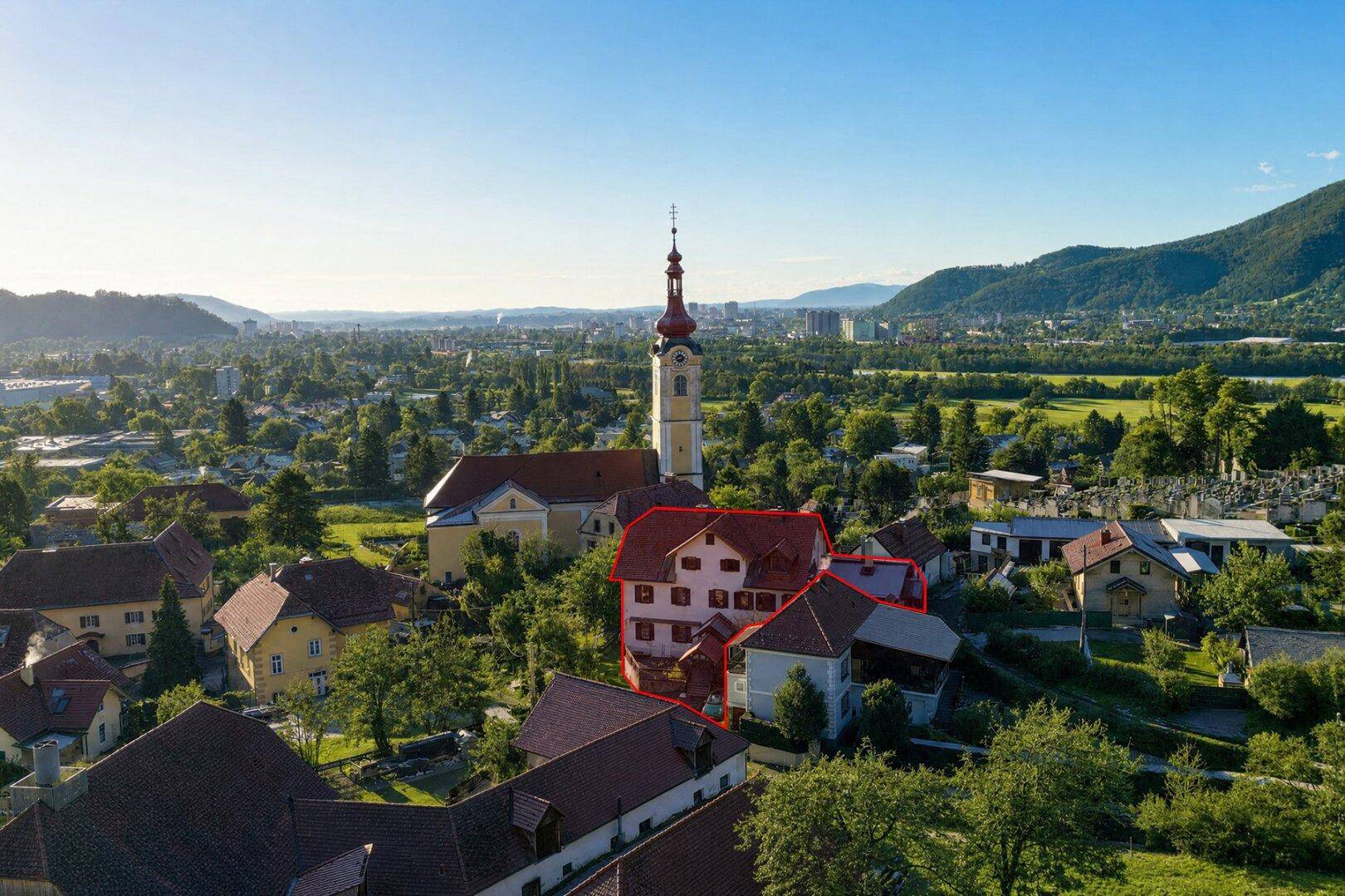 Panoramablick aus der Luft auf das Anwesen mit Kirche und umliegender Berglandschaft.