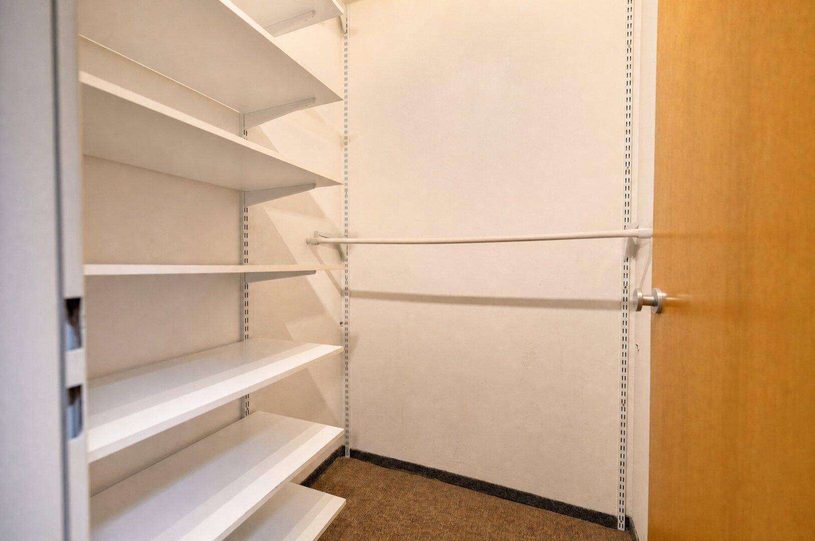 Praktischer begehbarer Kleiderschrank mit Regalen und Kleiderstange.