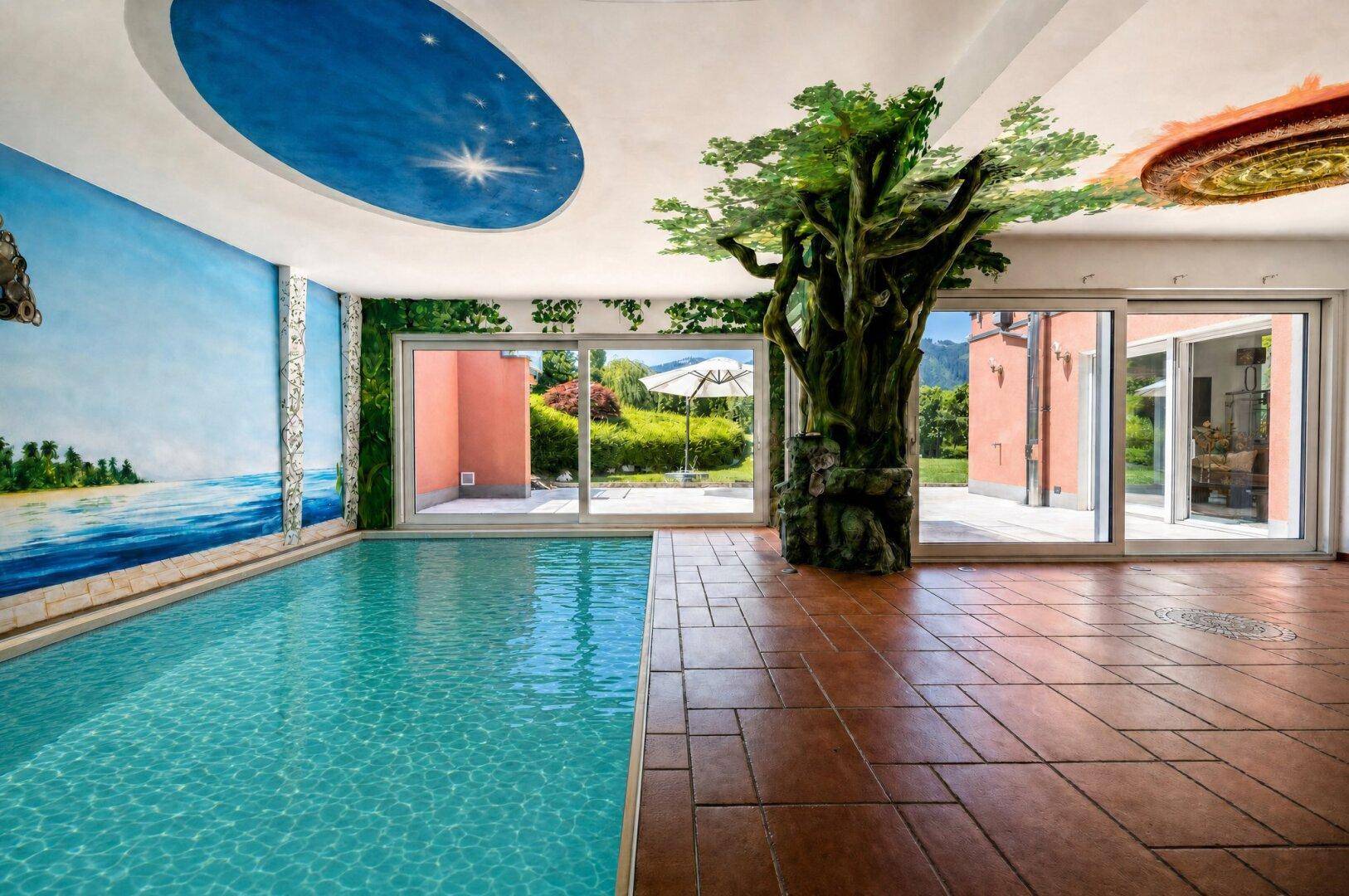 Innenpoolbereich mit künstlerischer Wandmalerei, großem Baumdekor und Zugang zum Außenbereich.
