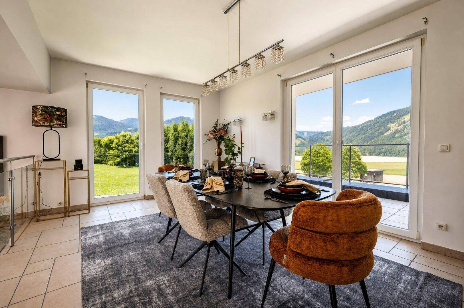 Eleganter Essbereich mit großem Esstisch, modernen Stühlen und weitem Blick auf die grüne Landschaft.