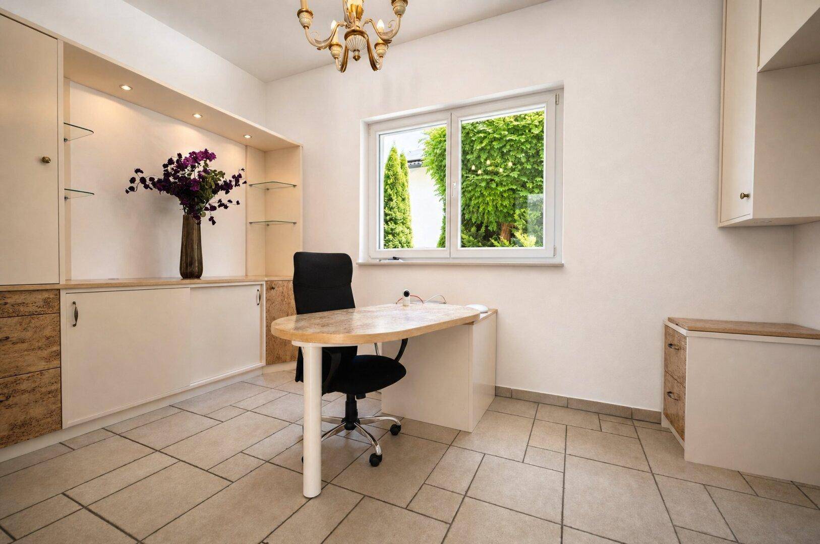 Helles Büro mit Einbauschränken, Schreibtisch und Fenster mit Blick auf die grüne Umgebung.