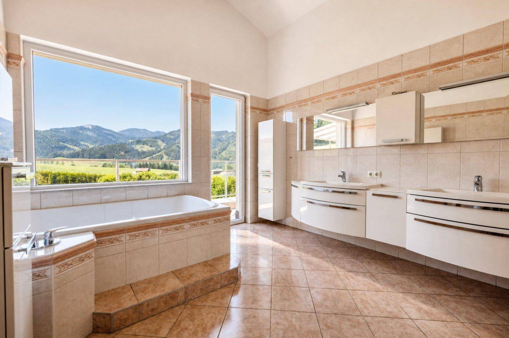 Geräumiges Badezimmer mit Badewanne, Doppelwaschbecken und Panoramablick auf die Berge.