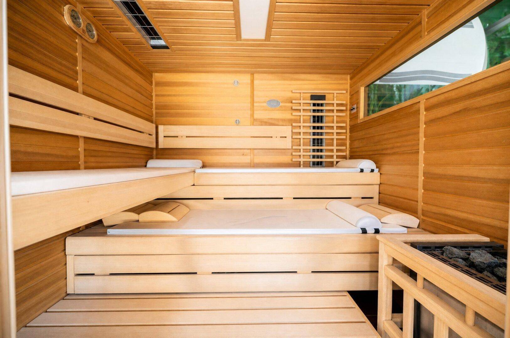 Moderne Holzsauna mit mehreren Bänken und integriertem Heizelement für Entspannung.