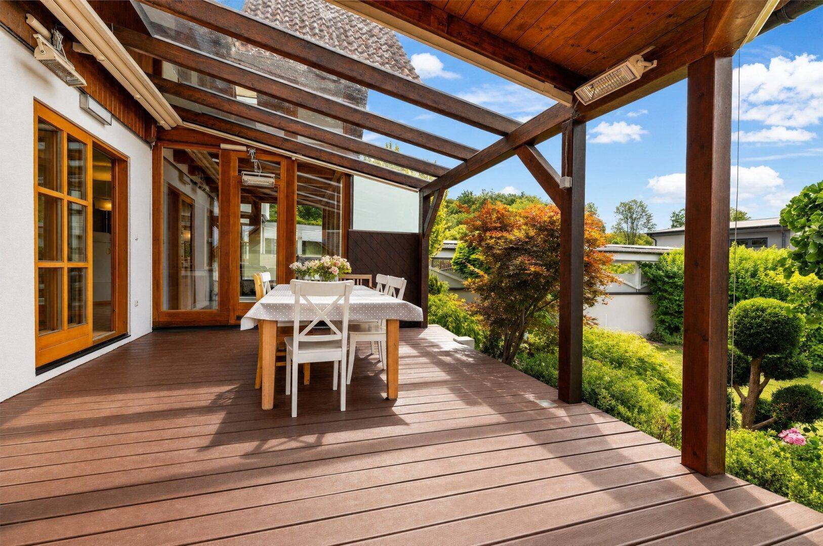 Große überdachte Holzterrasse mit Esstisch und Stühlen, ideal für Mahlzeiten im Freien.