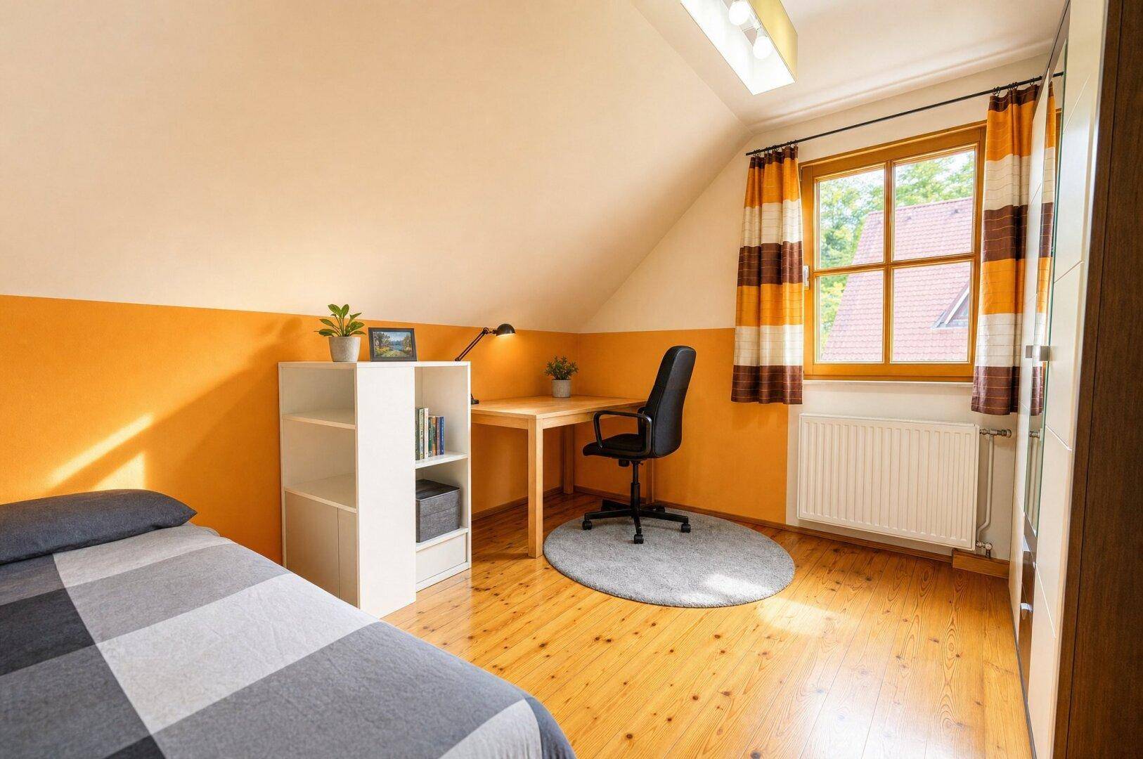 Helles Zimmer im Dachgeschoss mit Holzboden, Schreibtisch und farbiger Wandgestaltung.