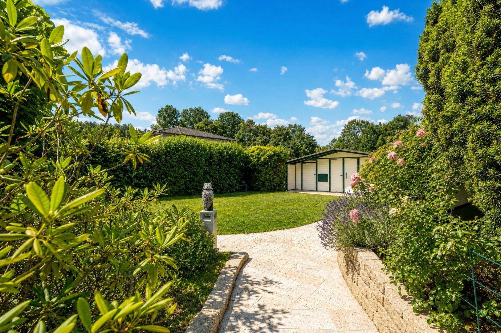 Gepflegter Gartenweg führt durch üppige Bepflanzung zu einem charmanten Gartenhaus.