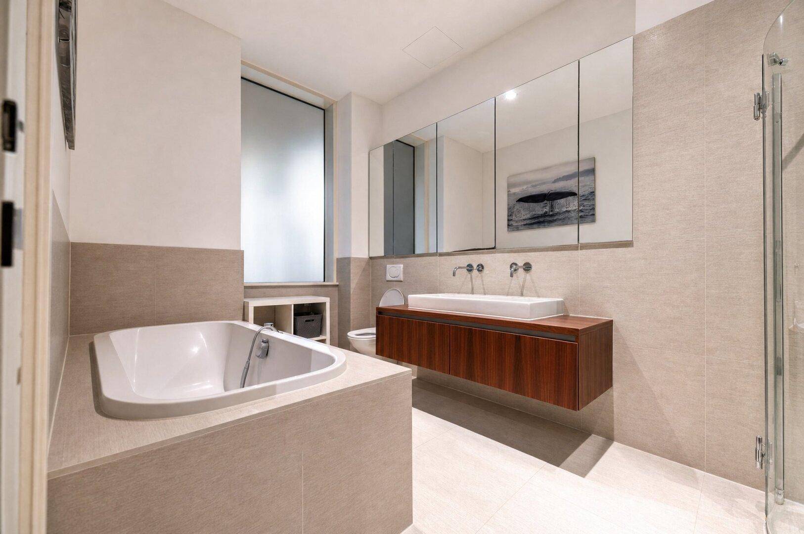 Modernes Badezimmer mit Badewanne, Doppelwaschbecken und großen Fliesen.