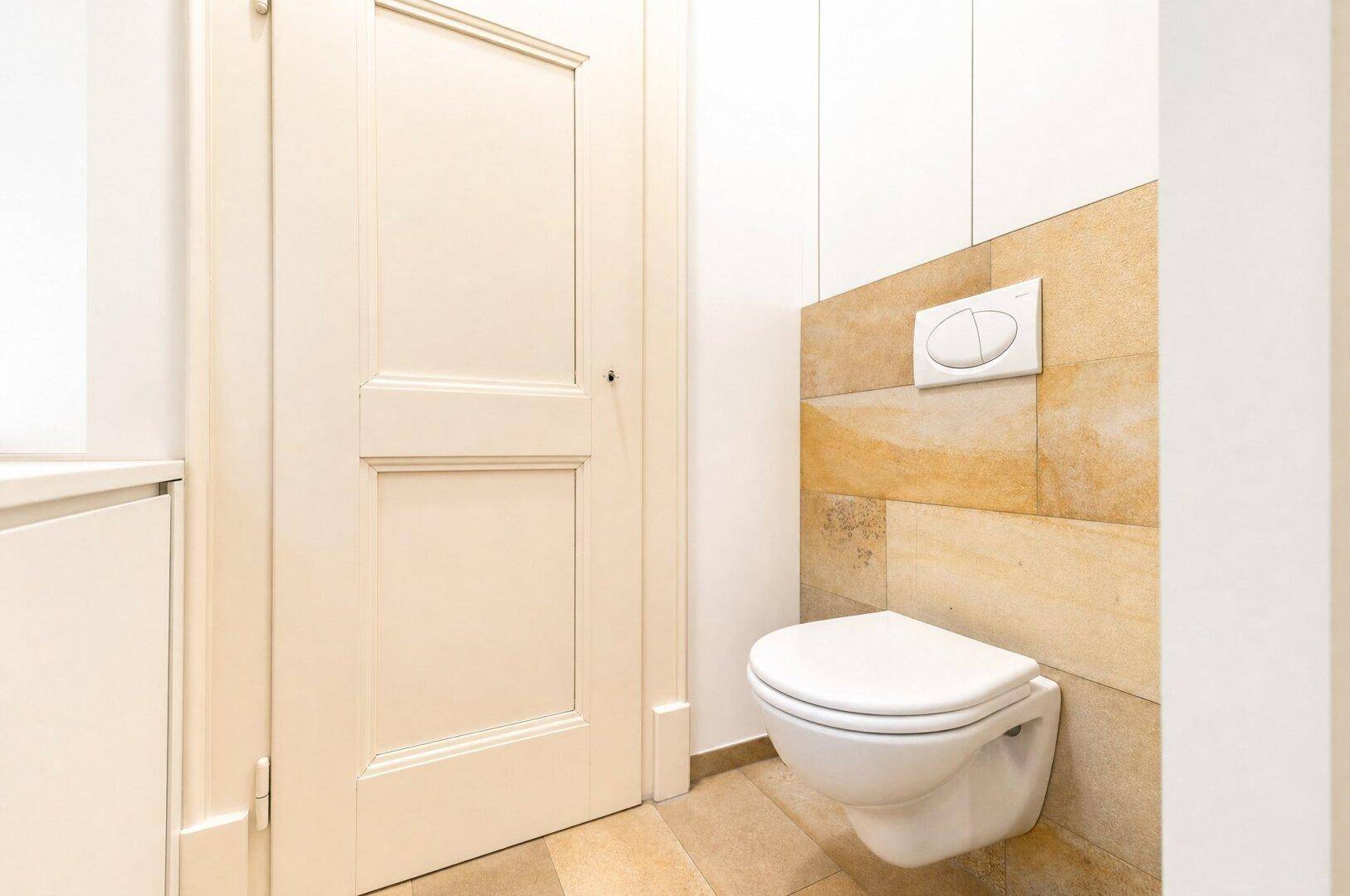 Separates WC mit Wand-WC und modernen Fliesen in hellem Design.