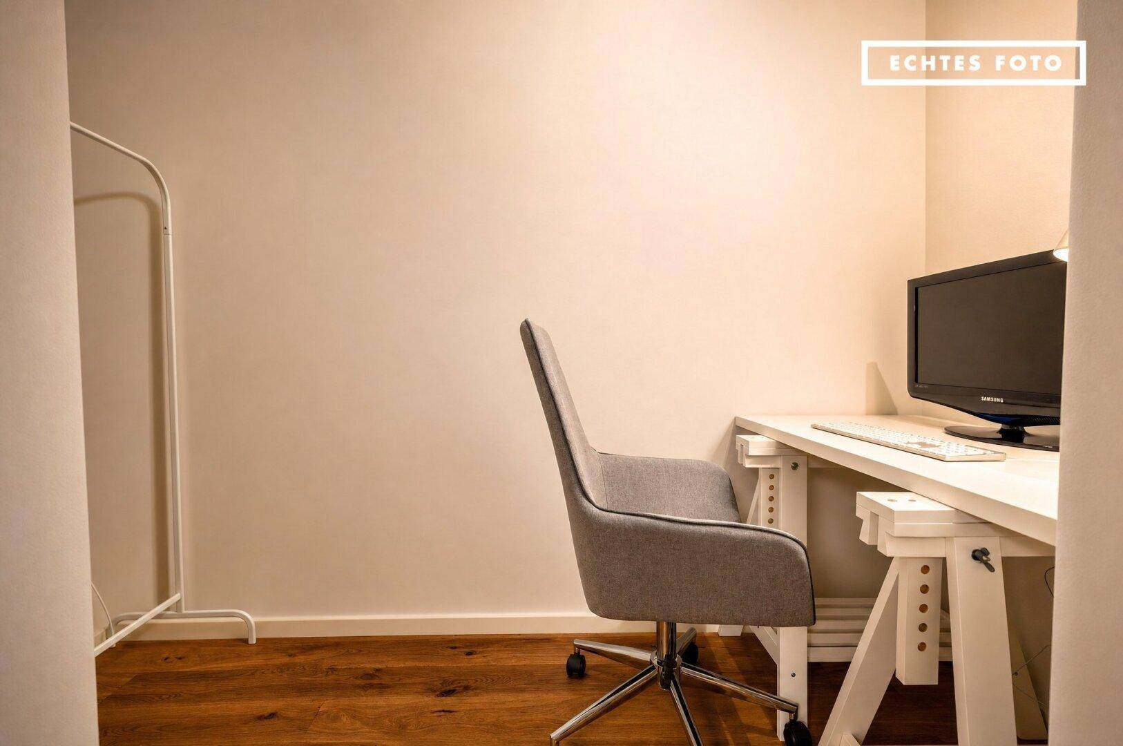 Funktionaler Arbeitsbereich mit Schreibtisch, Bürostuhl und Holzboden, ideal für Home-Office.