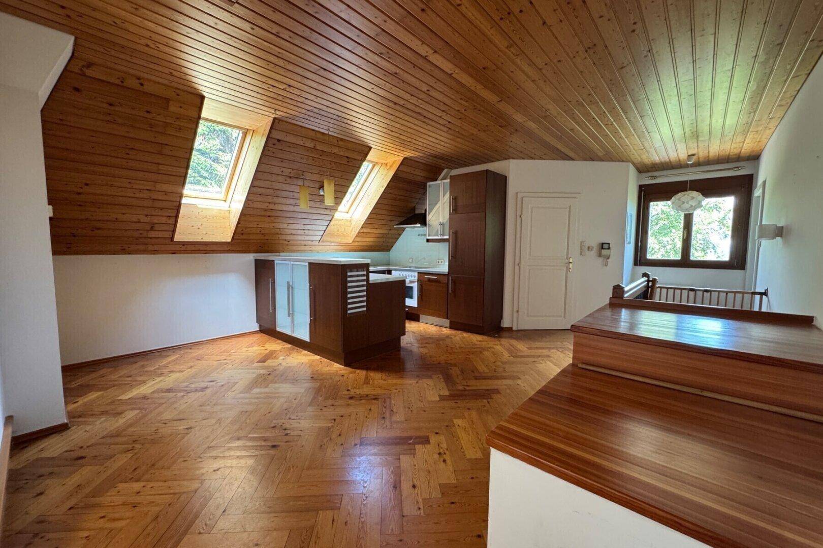 Offene Küche im Dachgeschoss mit Holzdecke, Fischgrätparkett und Dachfenstern.