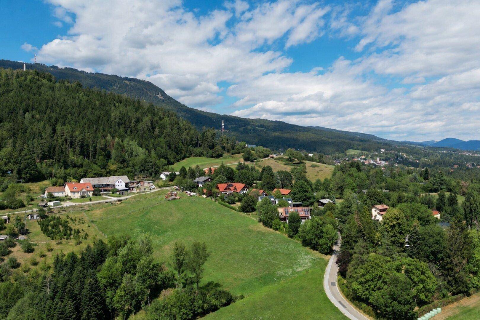 Malerische Luftaufnahme einer ländlichen Gegend mit grünen Hügeln und verstreuten Häusern.