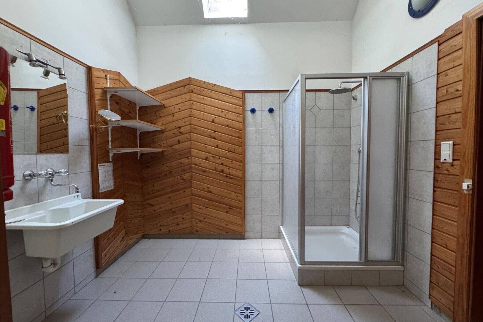 Geräumiges Badezimmer mit Duschkabine, Holzverkleidung und Oberlicht im Dachgeschoss.