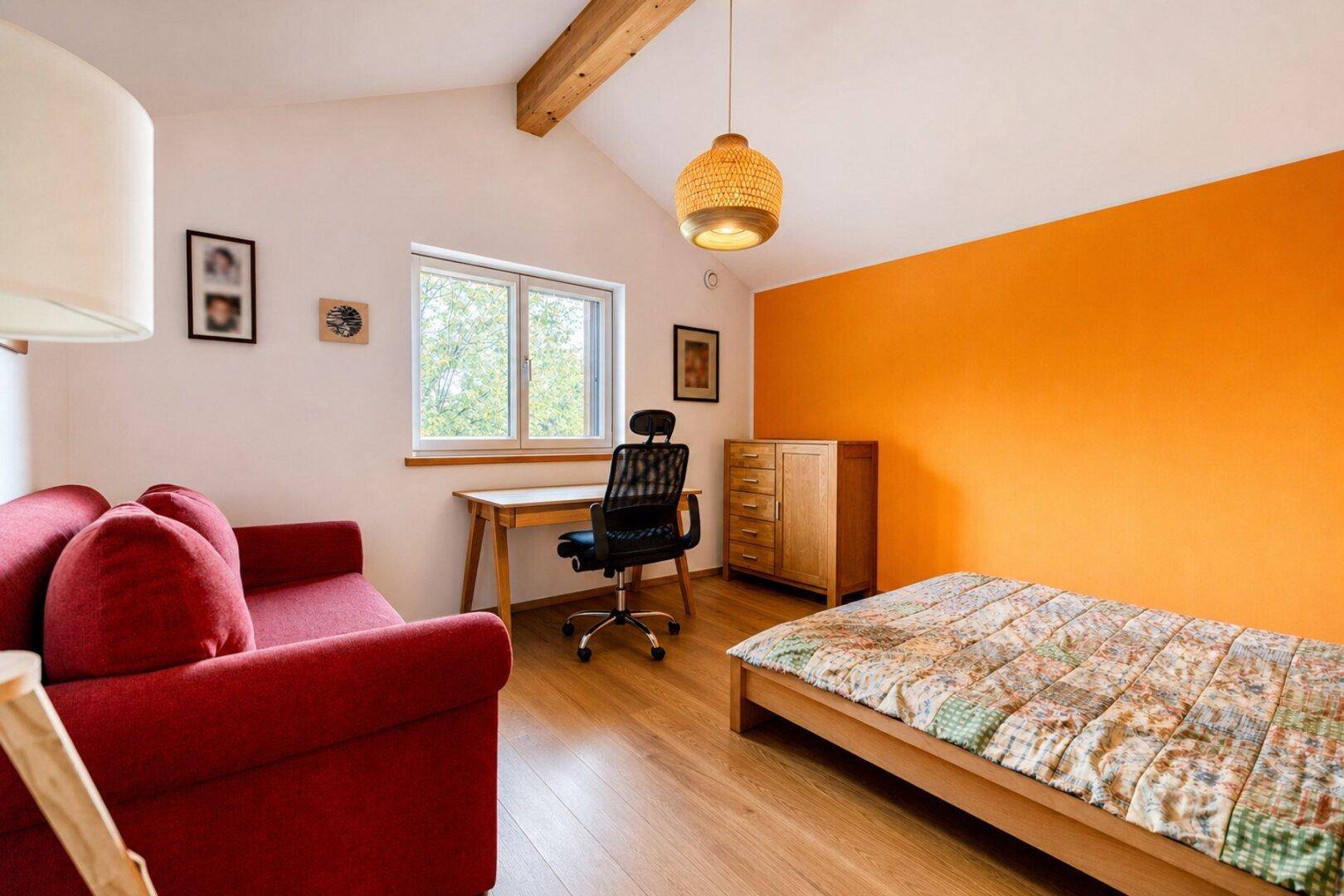 Gemütliches Schlafzimmer mit orangefarbener Akzentwand, Holzbalken und Schreibtisch.