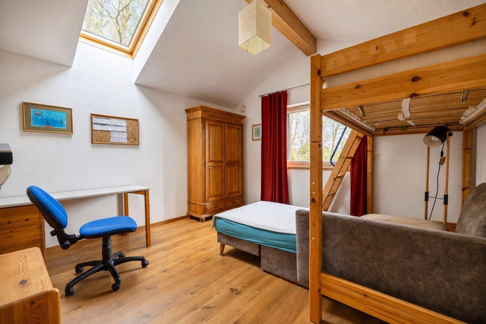 Kinderzimmer mit Etagenbett, Schreibtisch, Dachfenster und Holzbalken.