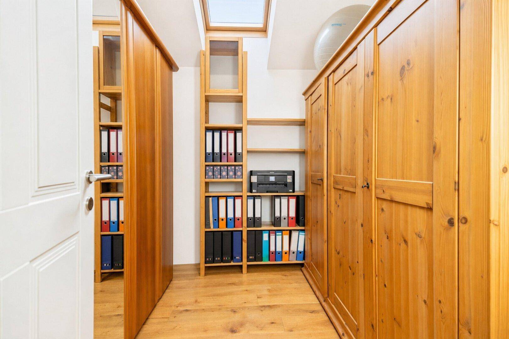 Praktischer Arbeitsraum mit Holzregalen, Schränken und Dachfenster für natürliches Licht.