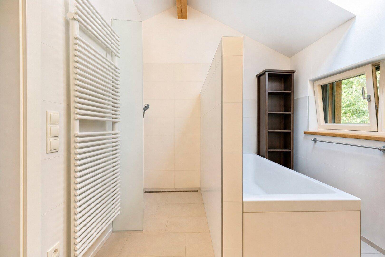 Modernes Badezimmer mit Badewanne, Duschbereich und beheiztem Handtuchhalter.