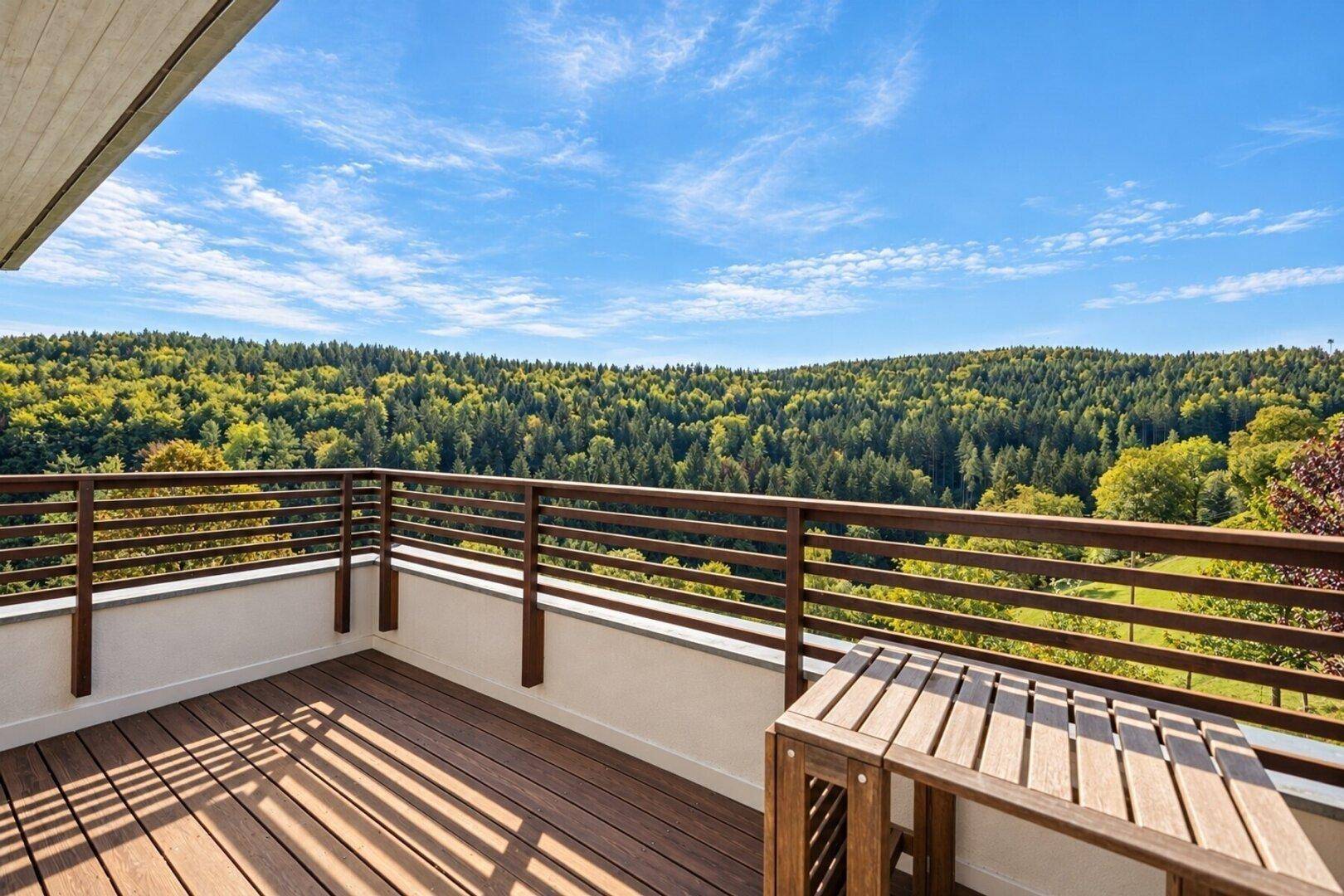 Geräumiger Balkon mit Holzboden und einem kleinen Tisch, ideal zum Entspannen mit Waldblick.